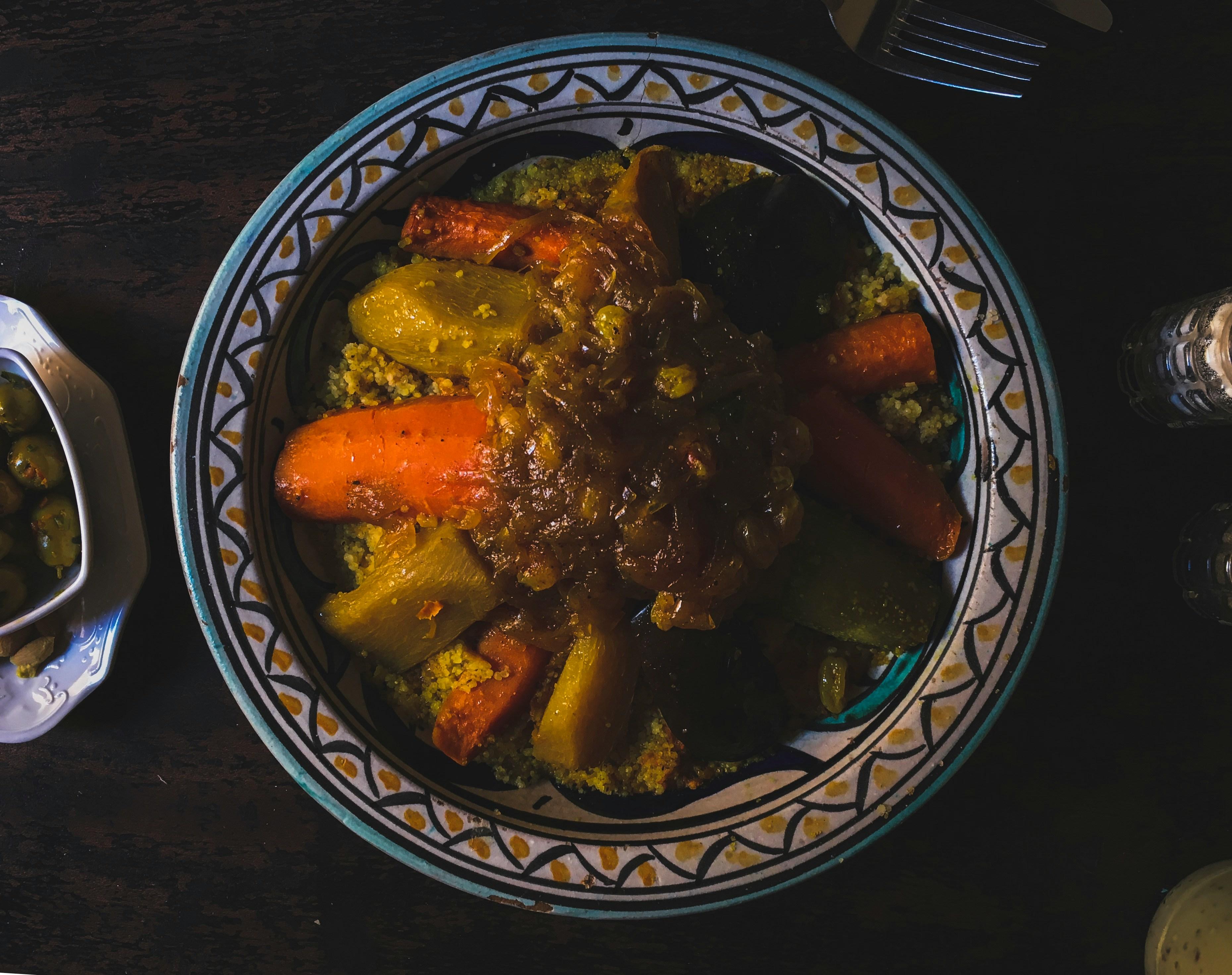 Steaming couscous with vegetables and broth in a deep platter